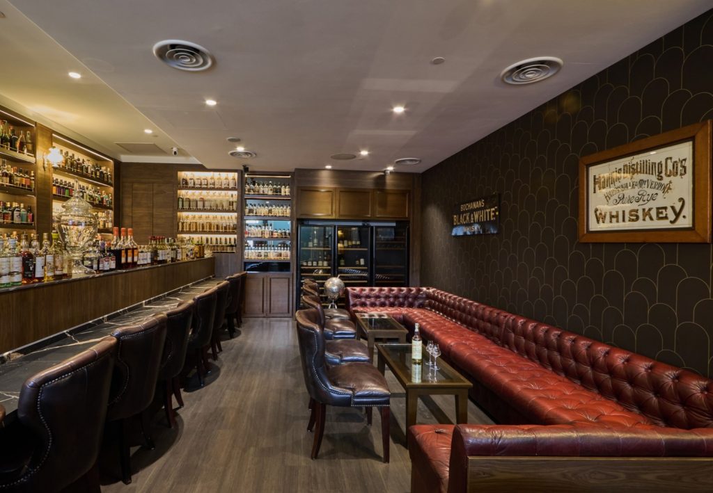 The warm cozy Library seating area of The Auld Alliance. Complemented by Art deco inspired wallpaper feature.