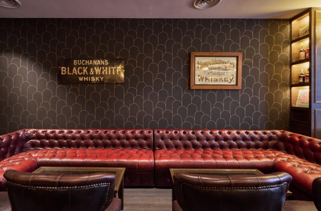 The warm cozy Library seating area of The Auld Alliance. Complemented by Art deco inspired wallpaper feature.